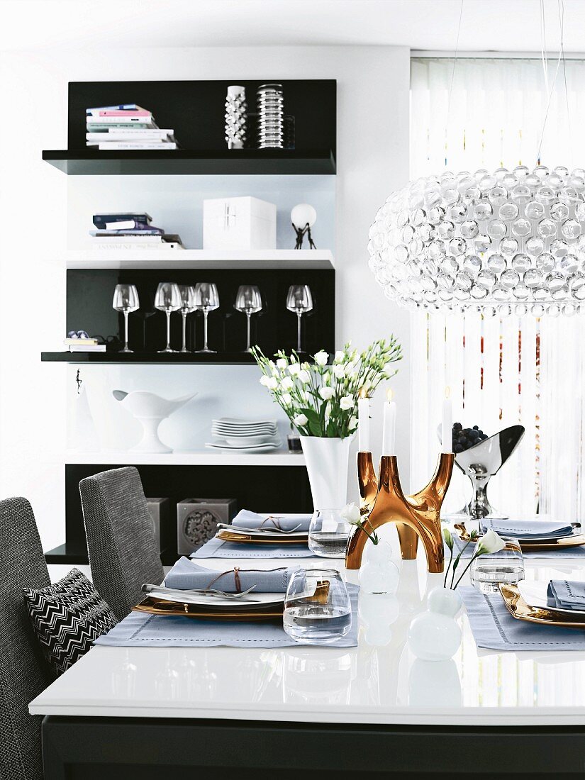 Dining table in black, white and grey with golden candlestick and crystal chandelier