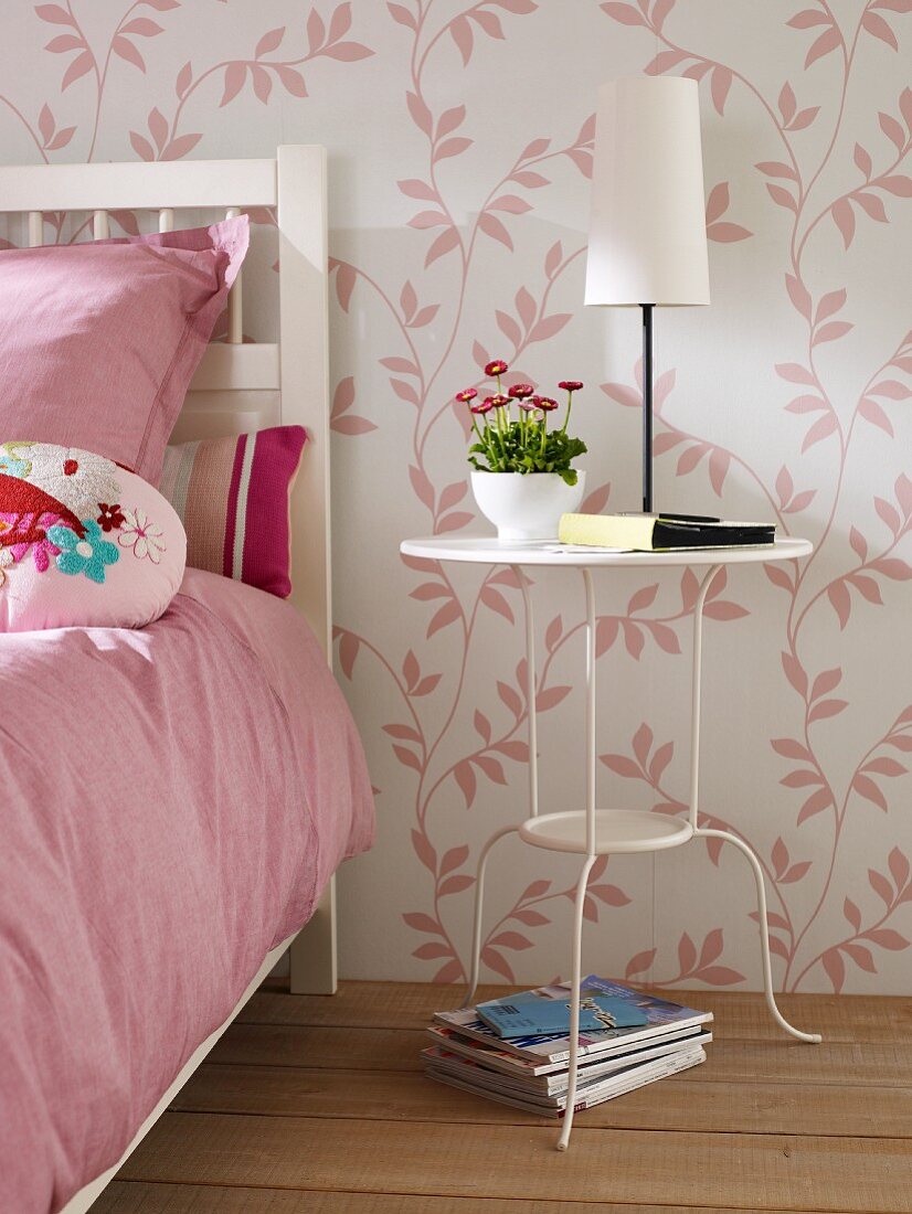 Weiß lackierte Metall-Beistelltisch neben Bett im Schlafzimmer mit rosa-weiß geblümter Tapete
