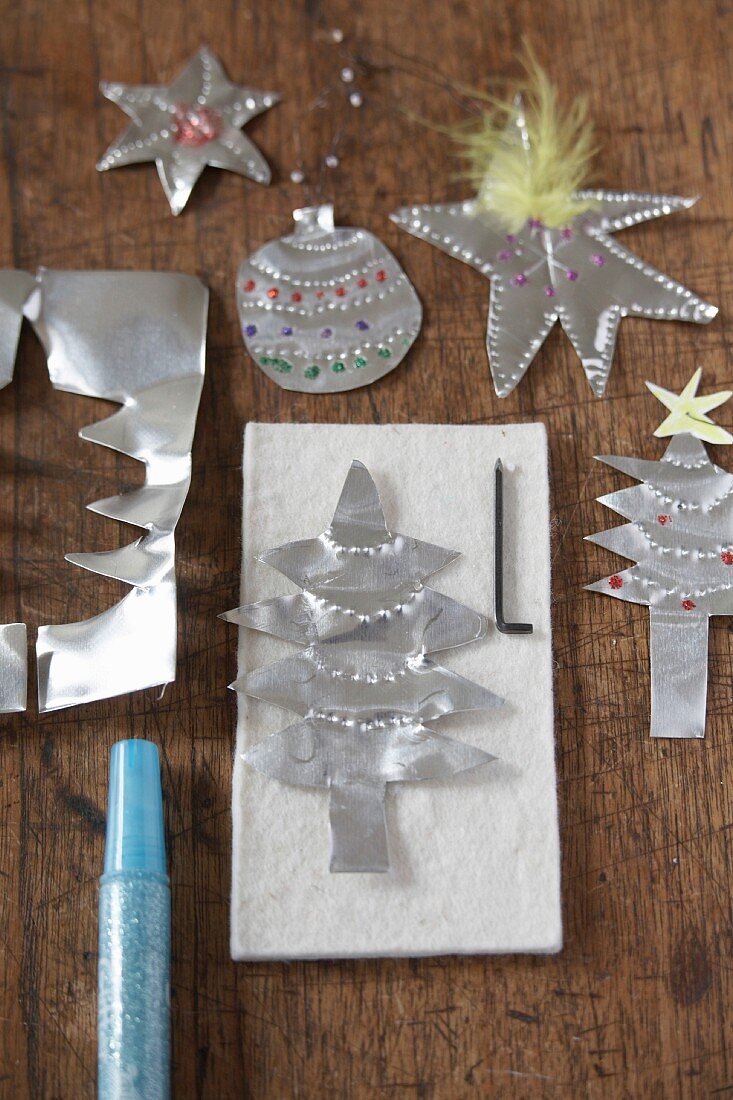 Christmas tree decorations cut out of silver paper on wooden surface