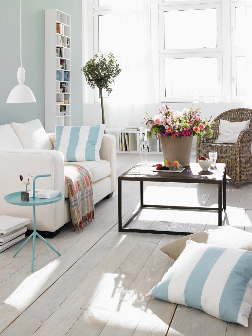 Wohnzimmer in Pastelltönen, weißer Couch und Blumenstrauß auf Couchtisch