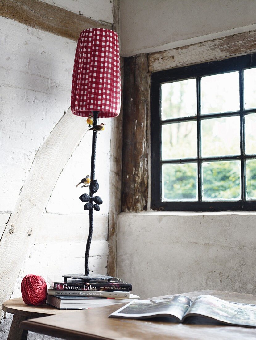 Metal lamp with red and white plaid lampshade in front of window