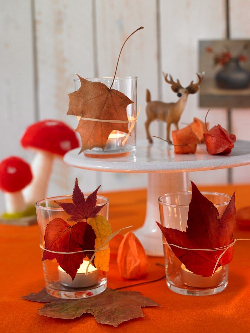 Gläser mit Teelichtern und Herbstblättern dekoriert