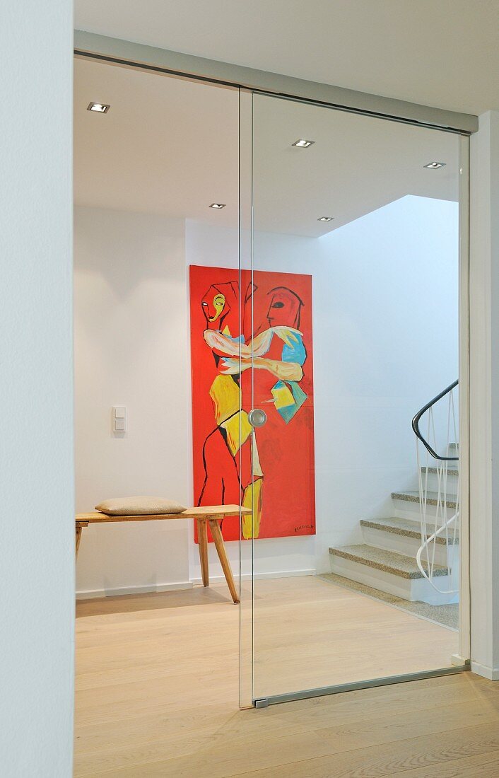 Geöffnete Glasschiebetür zum Flurbereich mit modernem Wandgemälde am Treppenaufgang