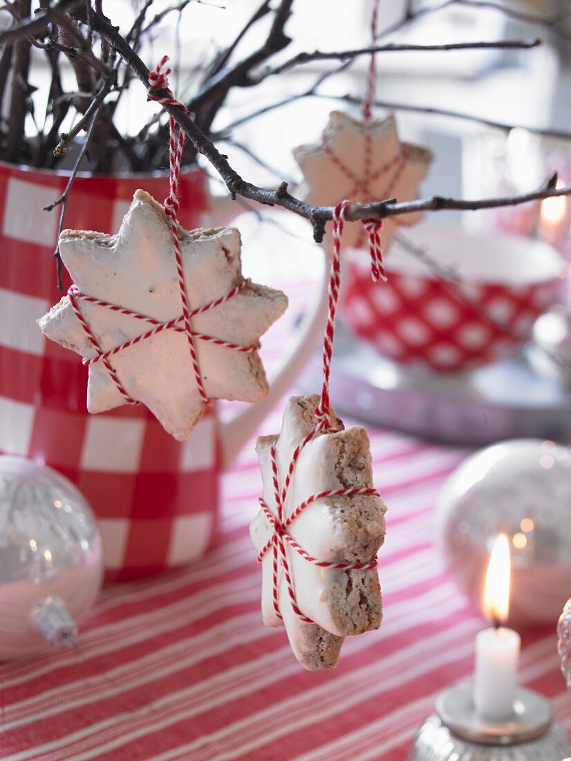 An Zweigen aufgehängte Zimtsterne als weihnachtliche Tischdekoration