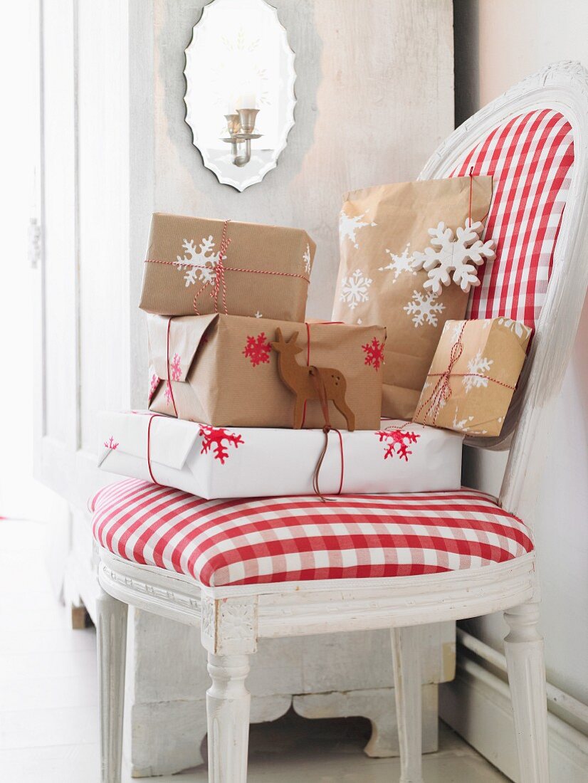 Verpackte Weihnachtsgeschenke auf Polsterstuhl mit rot-weiss kariertem Bezug