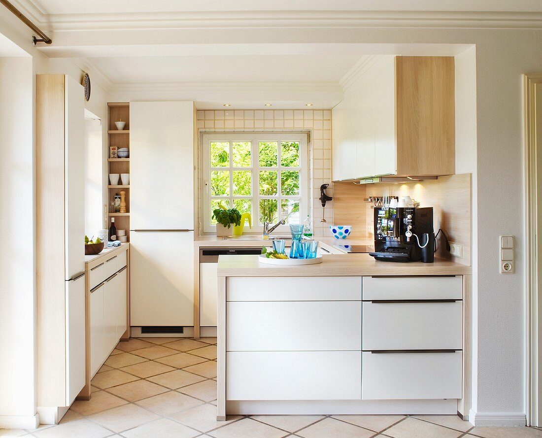 Pale fitted kitchen with wooden worksurfaces, lattice windows and tiled floor