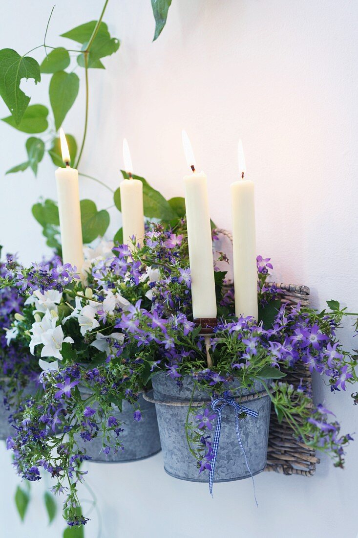 weiße Kerzen in verzinkten Bluemntöpfen mit Campanula und Petunien