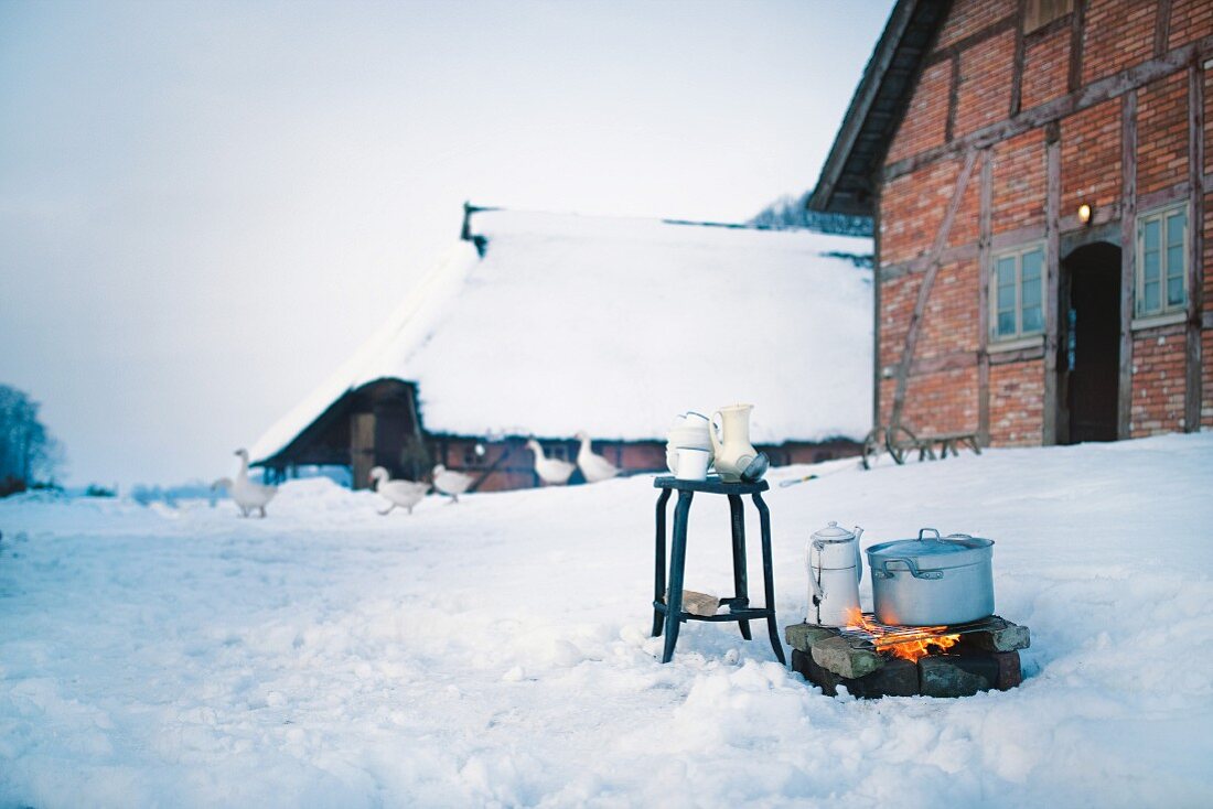 Feuerstelle vor schneebedecktem Fachwerkhaus