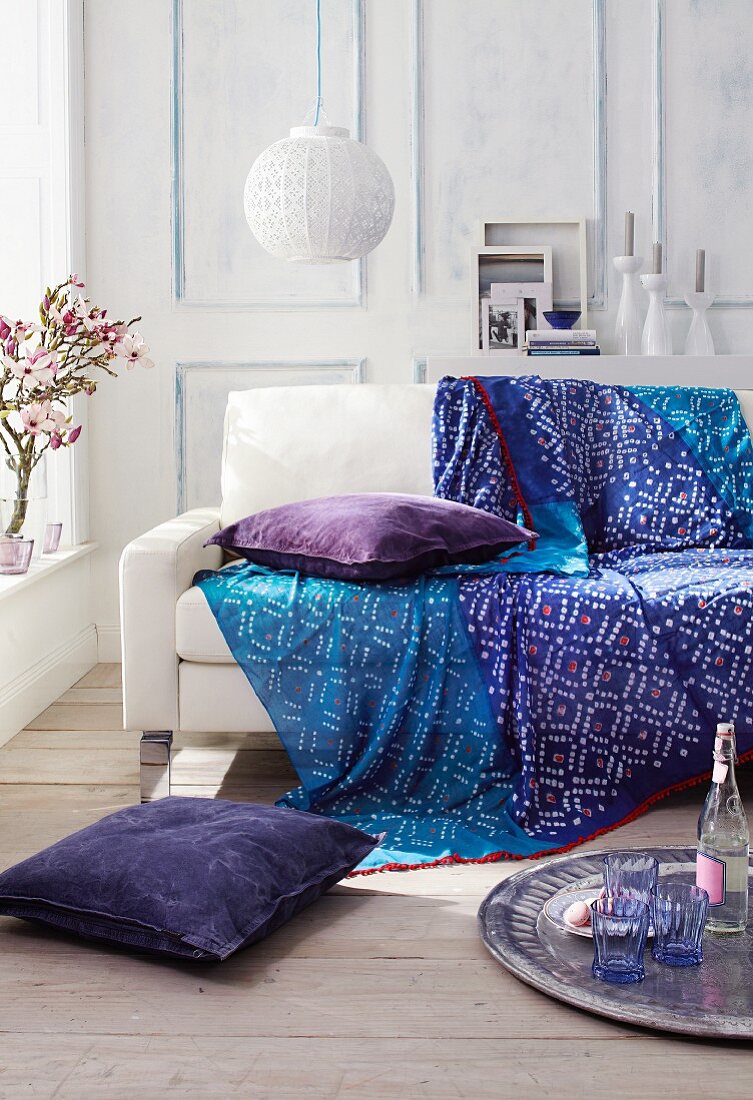 weiße Couch mit Decke in Blautönen im Wohnzimmer