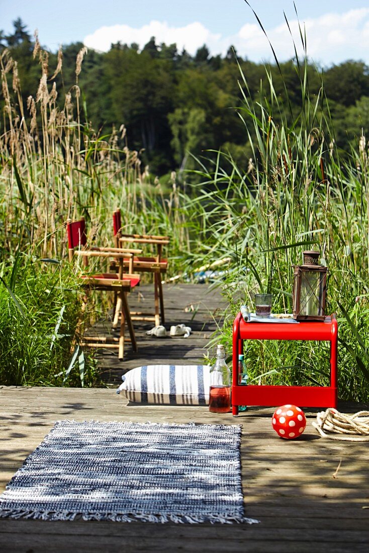 Directors' chairs & small table on boardwalk amongst reeds