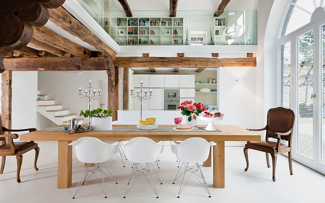 Offener Wohnraum in Weiß mit Holzbalkendecken & verglastem Galeriebereich