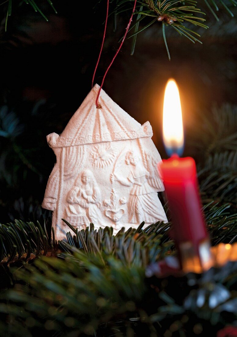 A nativty scene made of salt dough on Christmas tree with a burning candle