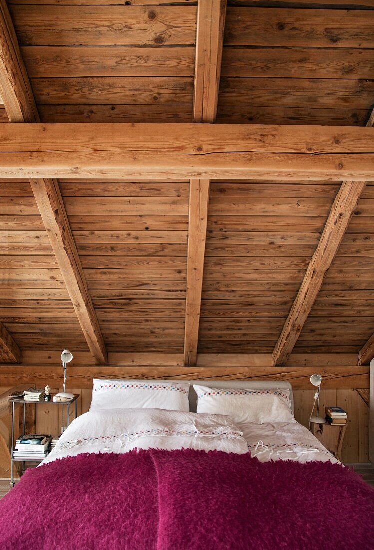 Schlafzimmer mit Bett unter Holzdachschräge