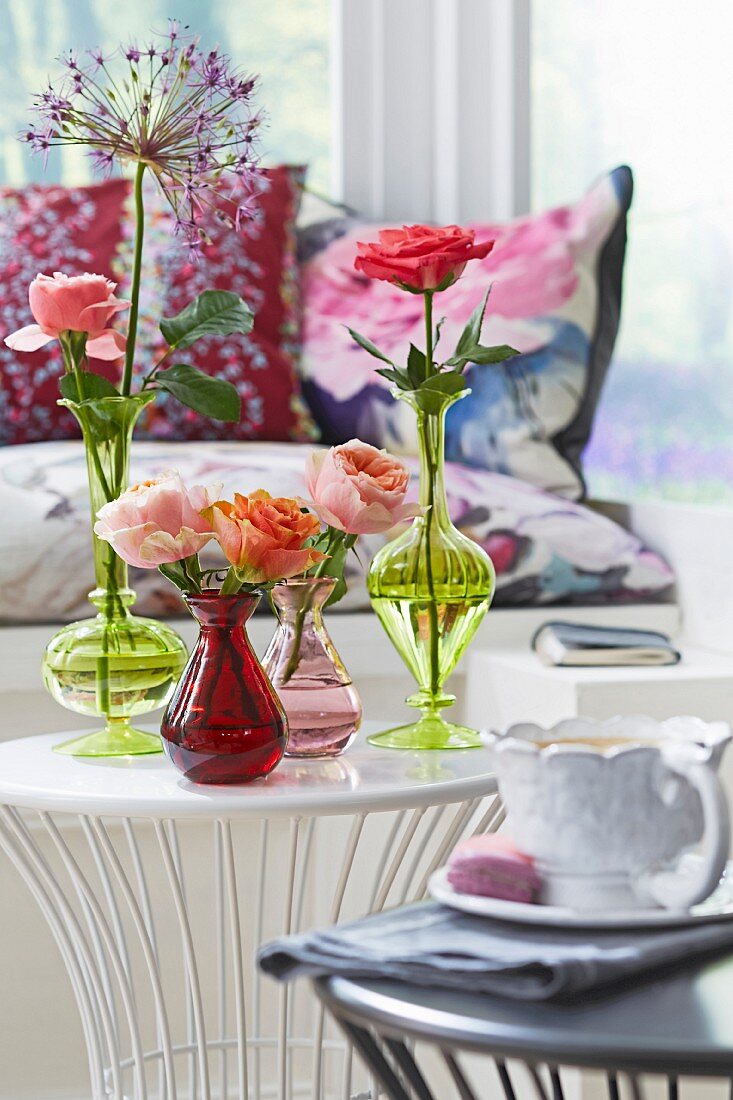 Rosen in verschiedenen Glasvasen auf Bestelltischchen