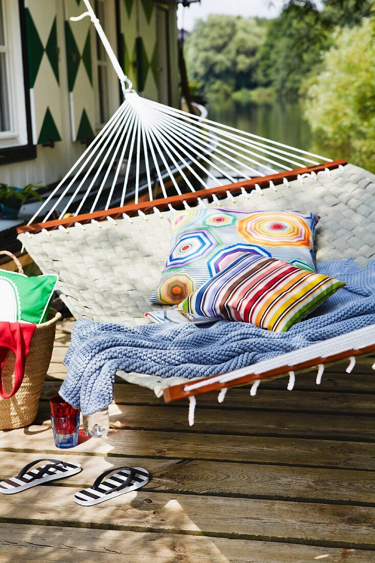 Hammock with colourful cushions & blanket outside boathouse