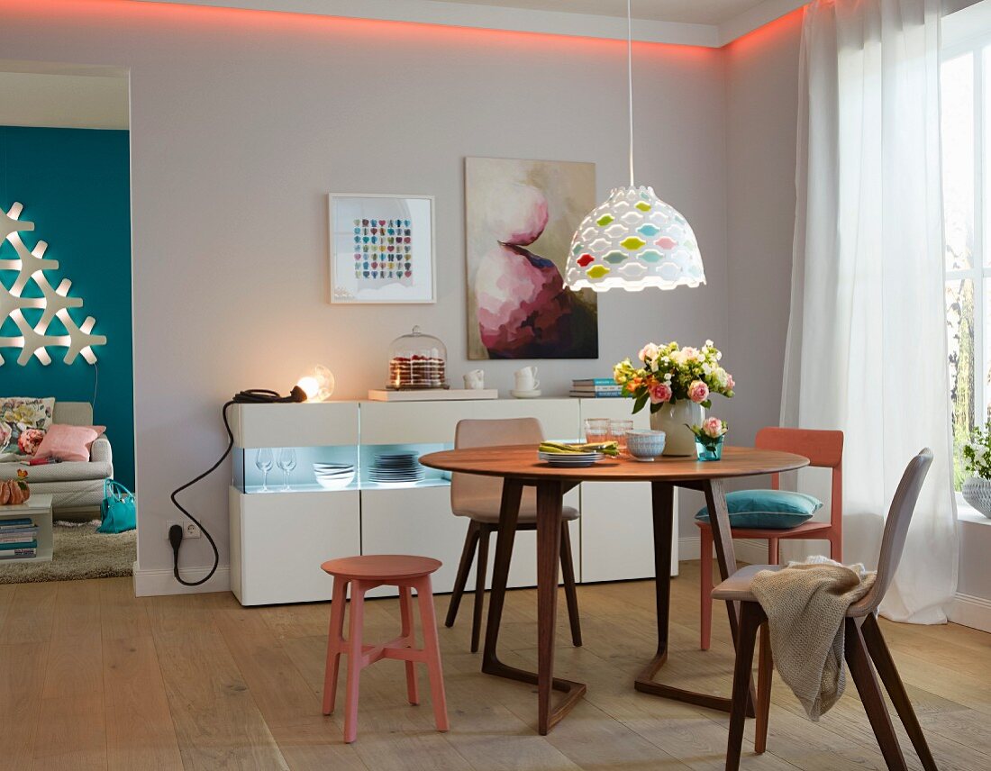 Esszimmer mit rundem Esstisch, Lichtleiste & beleuchtetem Sideboard
