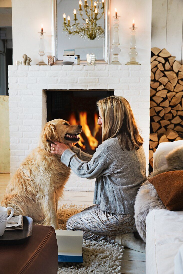 A woman with a dog in front of a fire