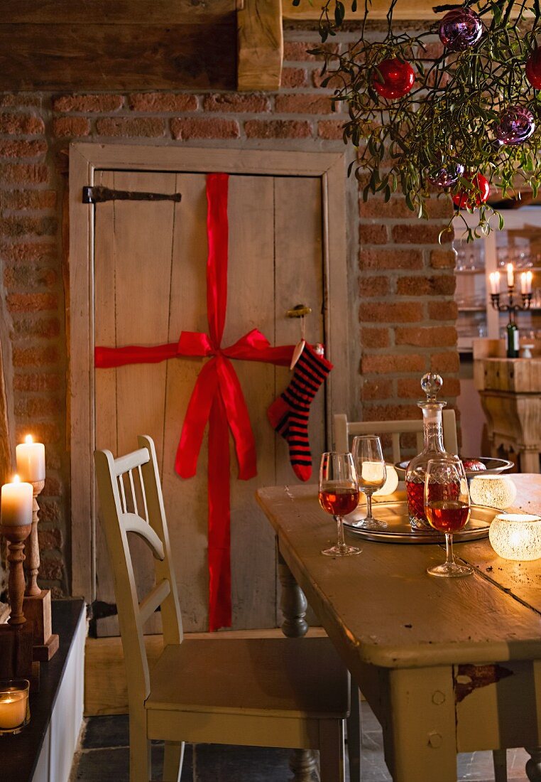 Holztür mit Schleife und Nikolausstrumpf, im Vordergrund Mistelzweige mit Weihnachtsdeko über Tisch