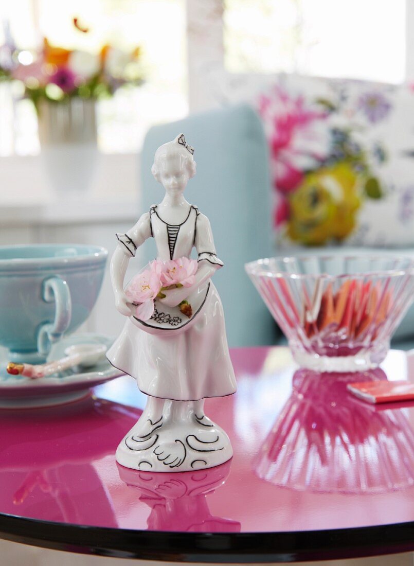 Blumenmädchen-Figur aus bemaltem Porzellan auf runder Tischplatte in spiegelndem Magenta