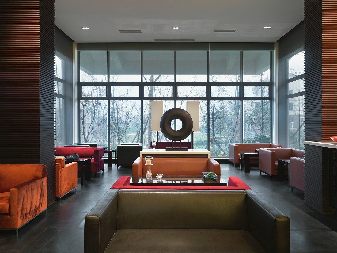 Clubatmosphäre - Tische und Polstersitzmöbel im Raum mit Glasfassade in zeitgenössischer Architektur