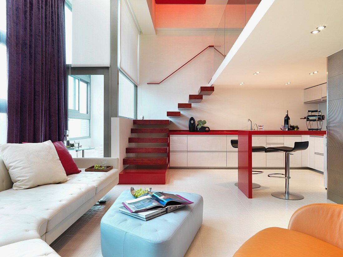 Farbige Polstermöbel und offene Küche im modernen Wohnraum mit Treppenaufgang