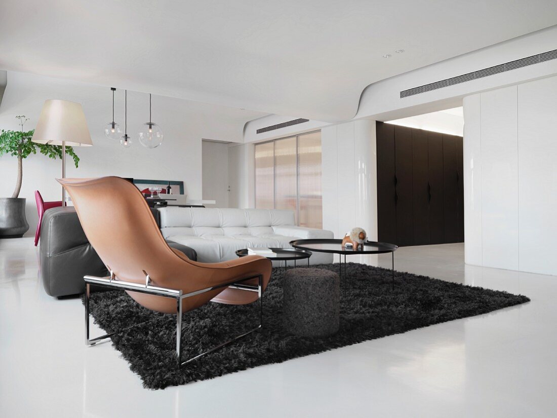 Brauner Designer Sessel und schwarzer Flokati im loftartigen Wohnraum
