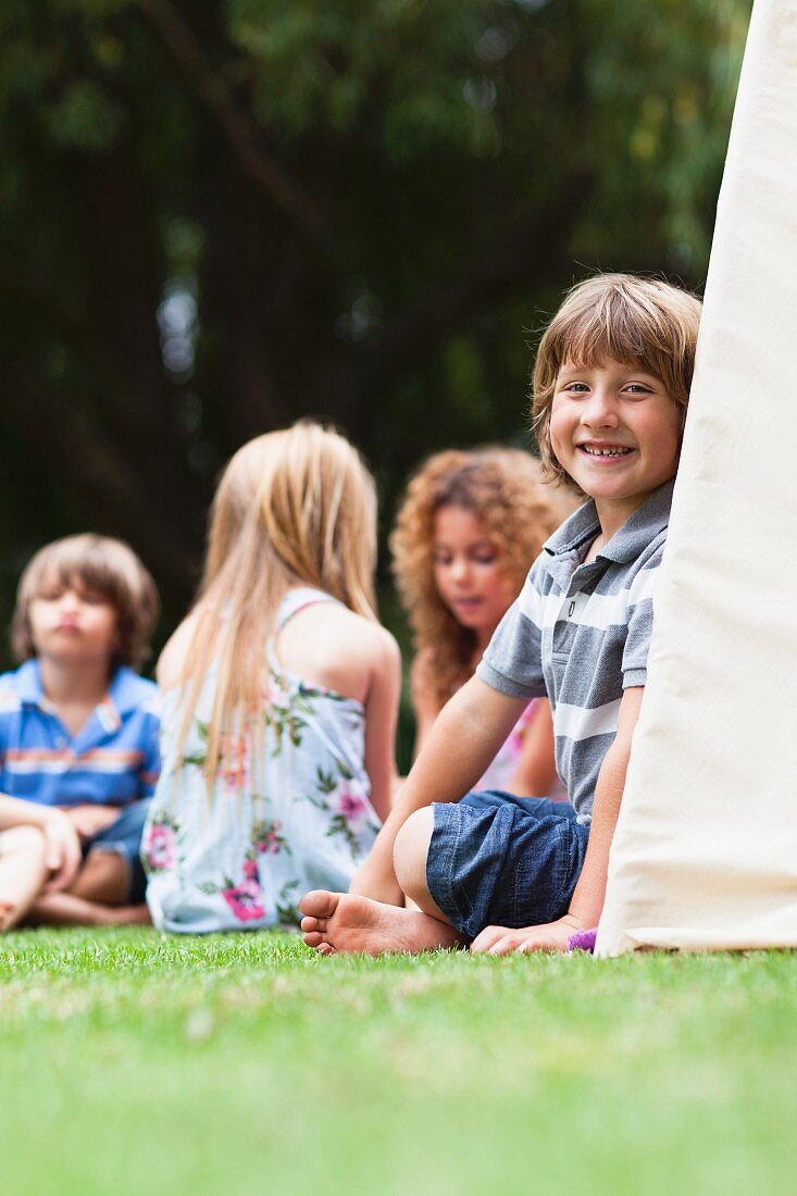 Kinder sitzen vor einem Zelt im Garten
