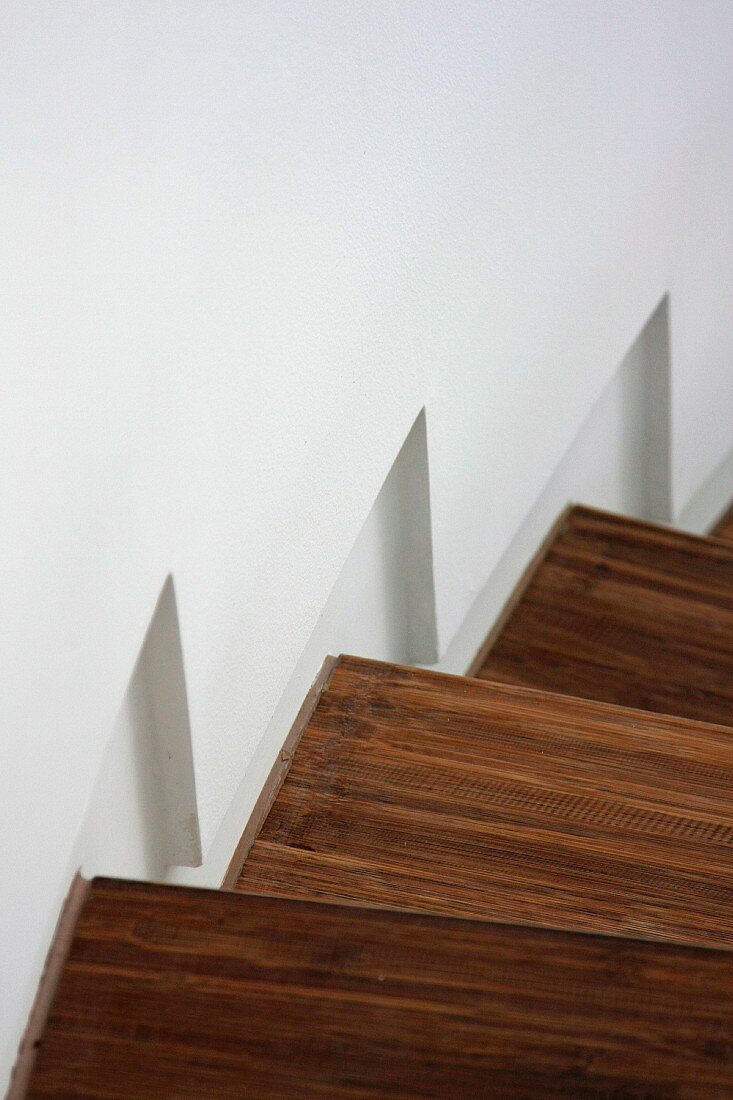 Detail wooden staircase along white wall