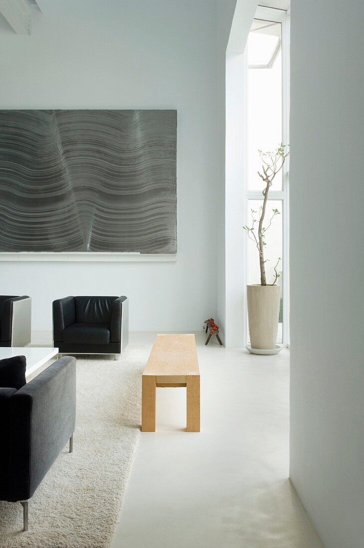 Gradlinige Polstermöbel und schlichte Holzbank im modernen Wohnraum mit Fenstererker