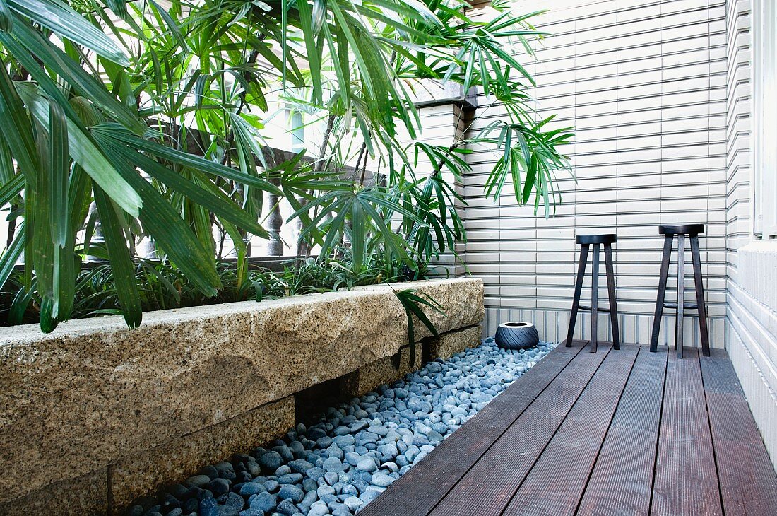 Barhocker auf Holzterrasse im asiatischen Stil mit Pflanzbecken aus Naturstein