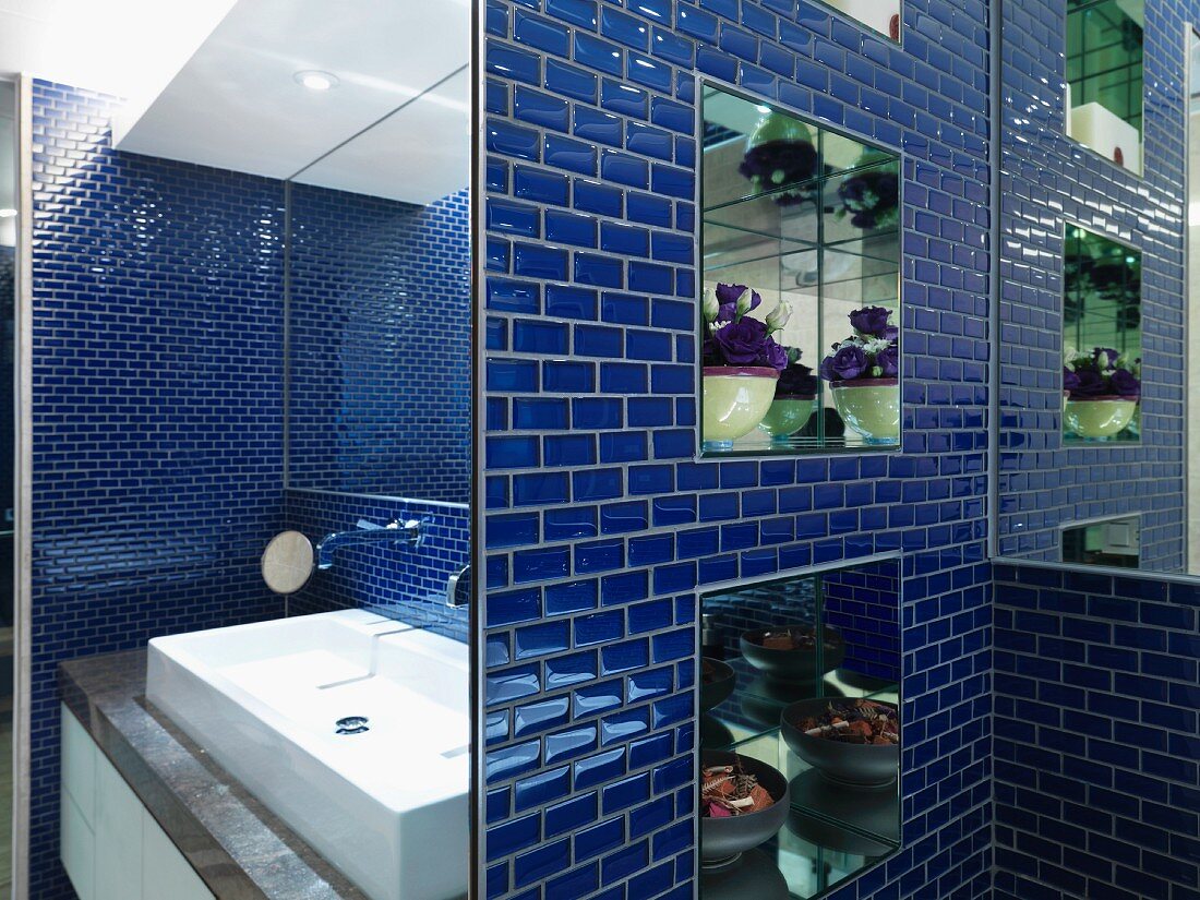 Badezimmer mit Spiegelnischen in der mit blau glänzenden Mosaikfliesen belegten Wand