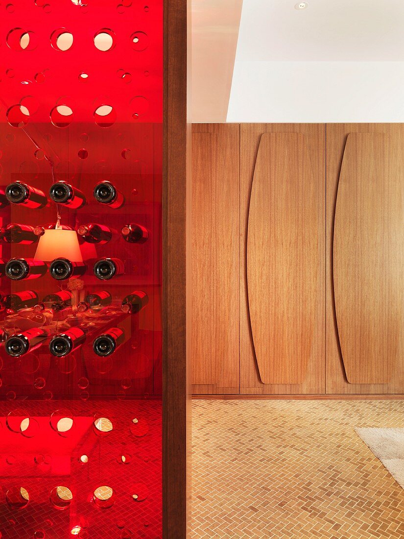 Red plastic wine rack and wood-panelled walls in background