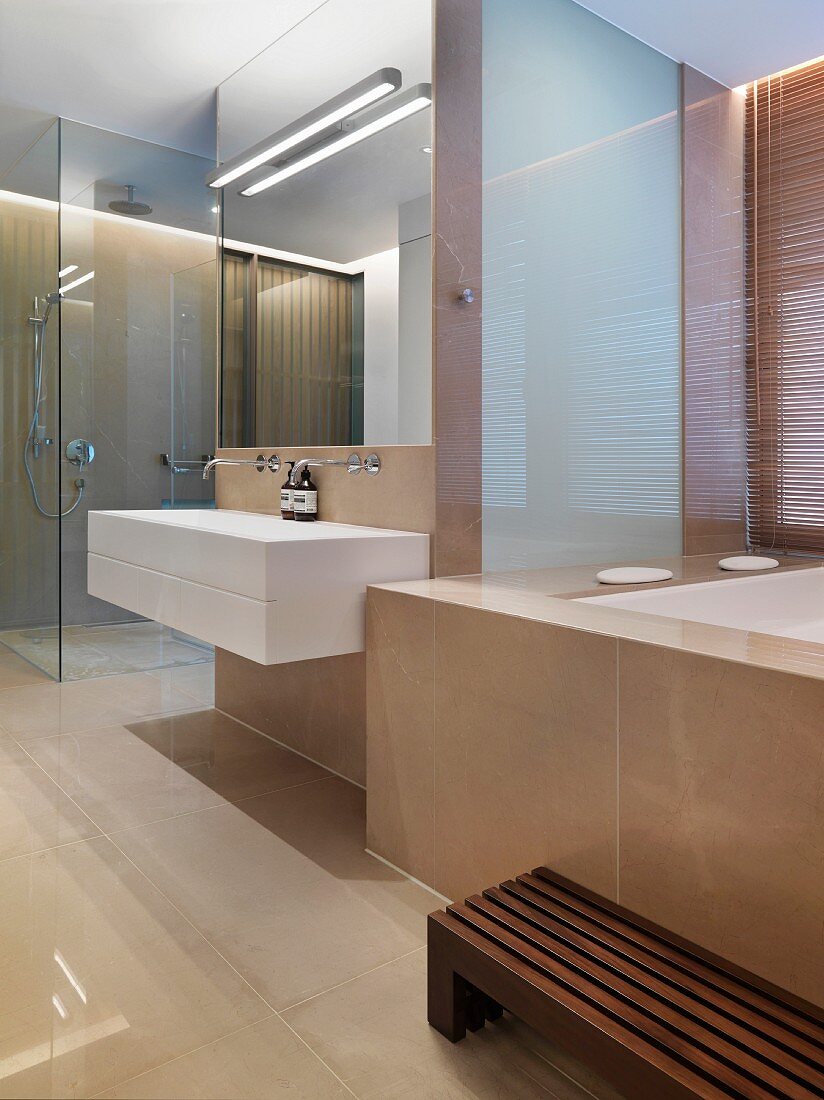 Modernes Designerbad mit marmorverkleideter Wanne und Glasabtrennung zur bodengleichen Dusche