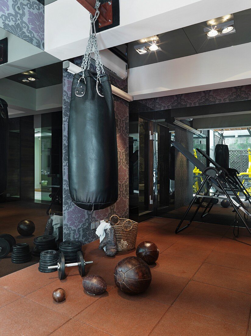Eleganter Fitnessraum mit Boxsack vor floral gemusterten Wänden und dunklen Spiegeln