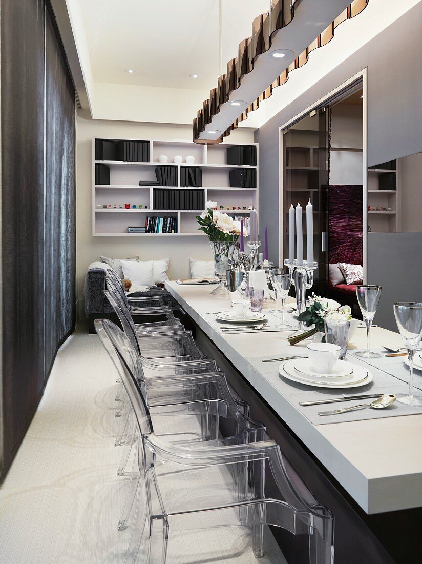 Classic modern dining area with festively set white table and designer chairs of acrylic glass