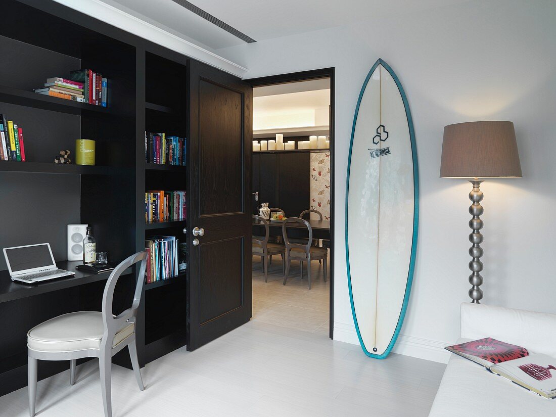 Moderner Wohnraum mit Home Office und Surfbrett neben der Tür zum Esszimmer
