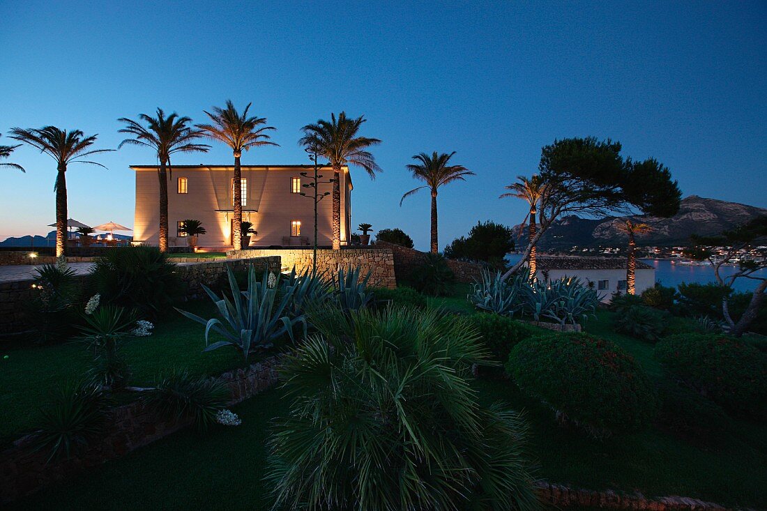 Mediterrane Gartenanlage und beleuchtetes Haus in Nachtstimmung