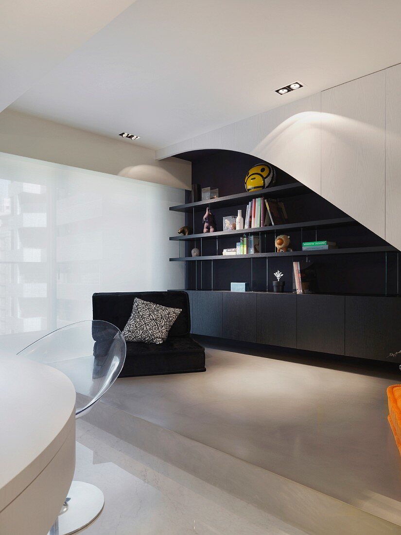 Moderner Wohnraum - schwarzer Bodensessel vor schwarz weißem Einbauregal auf Podest