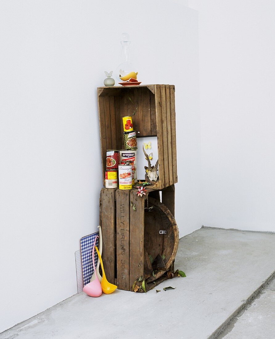 Lebensmitteldosen in Vintage Holzkistenstapel und Retro Schöpflöffel aus farbigem Kunststoff an Wand