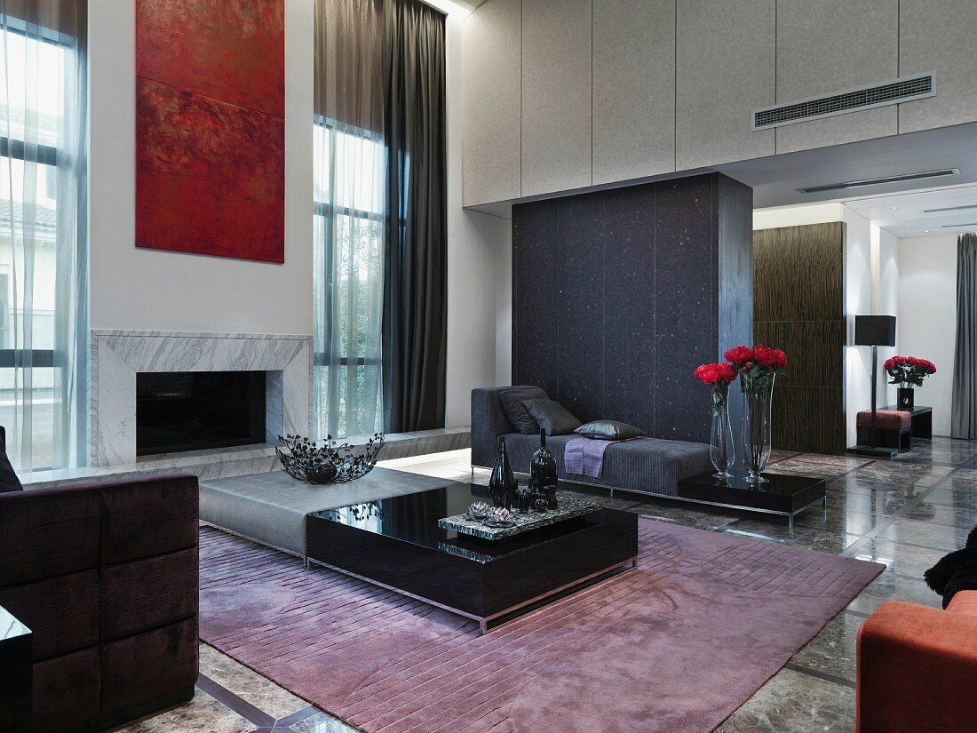 Eleganter Wohnraum im Designerstil mit Bodentischen auf Teppich und verschiedenen Polstermöbeln