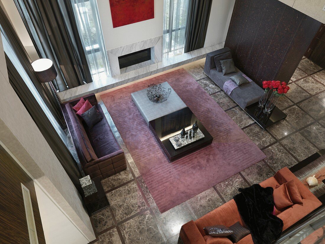 Blick auf verschiedene Polstermöbel um Bodentisch auf Teppich im minimalistischen Wohnraum mit grauem Steinboden
