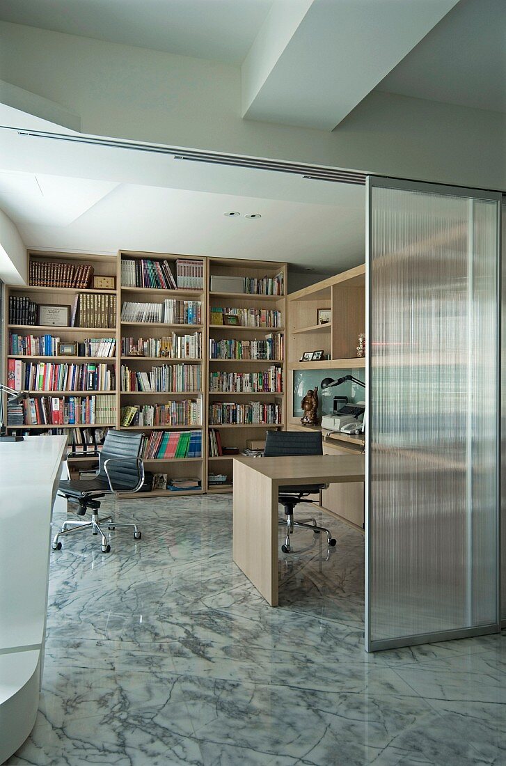 Wohnraum mit Steinboden und Blick durch offene Glasschiebetür in Arbeitsbereich