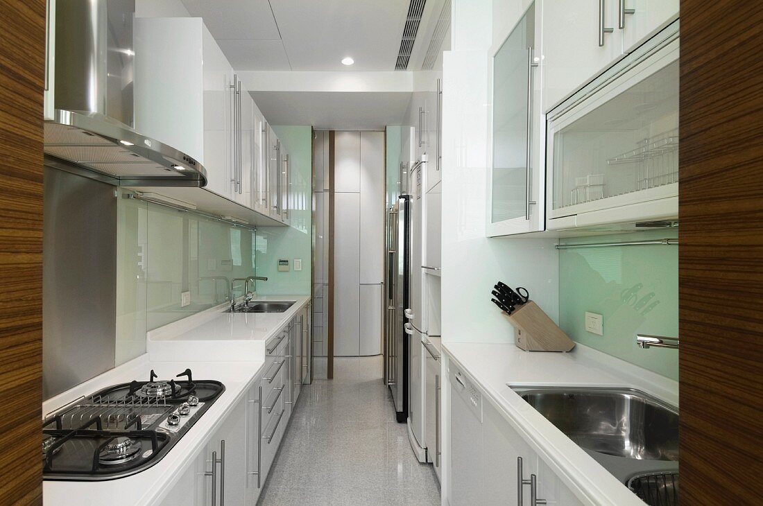Schmale Küche in Weiß mit Hängeschränken über Küchenzeile im Designerstil