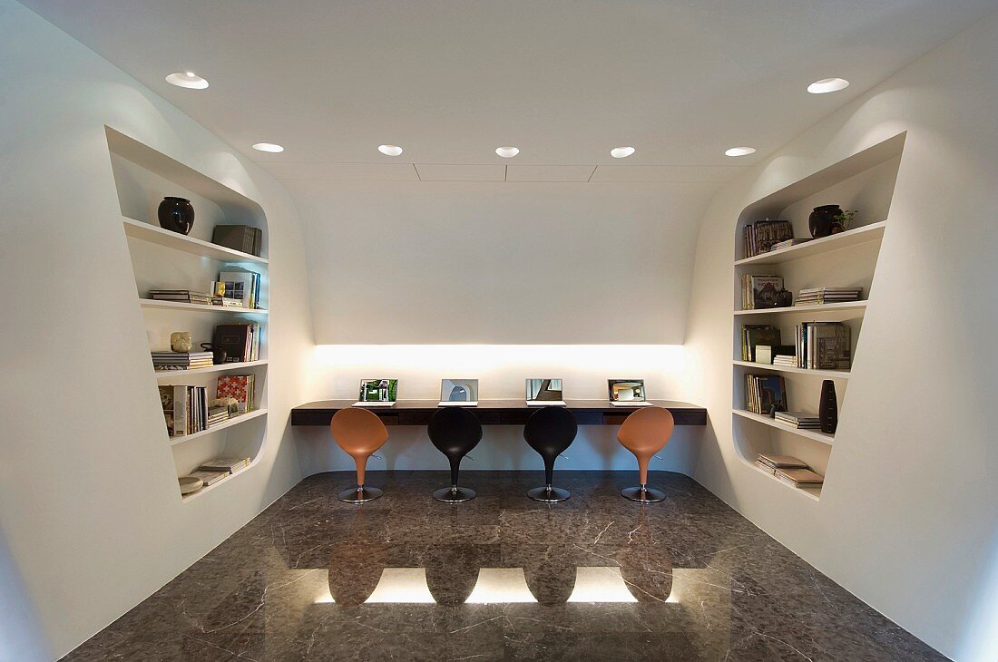 Arbeitsbereich mit Schalenstühlen auf hochglänzendem Steinboden und futuritische Raumteiler mit integriertem Regal