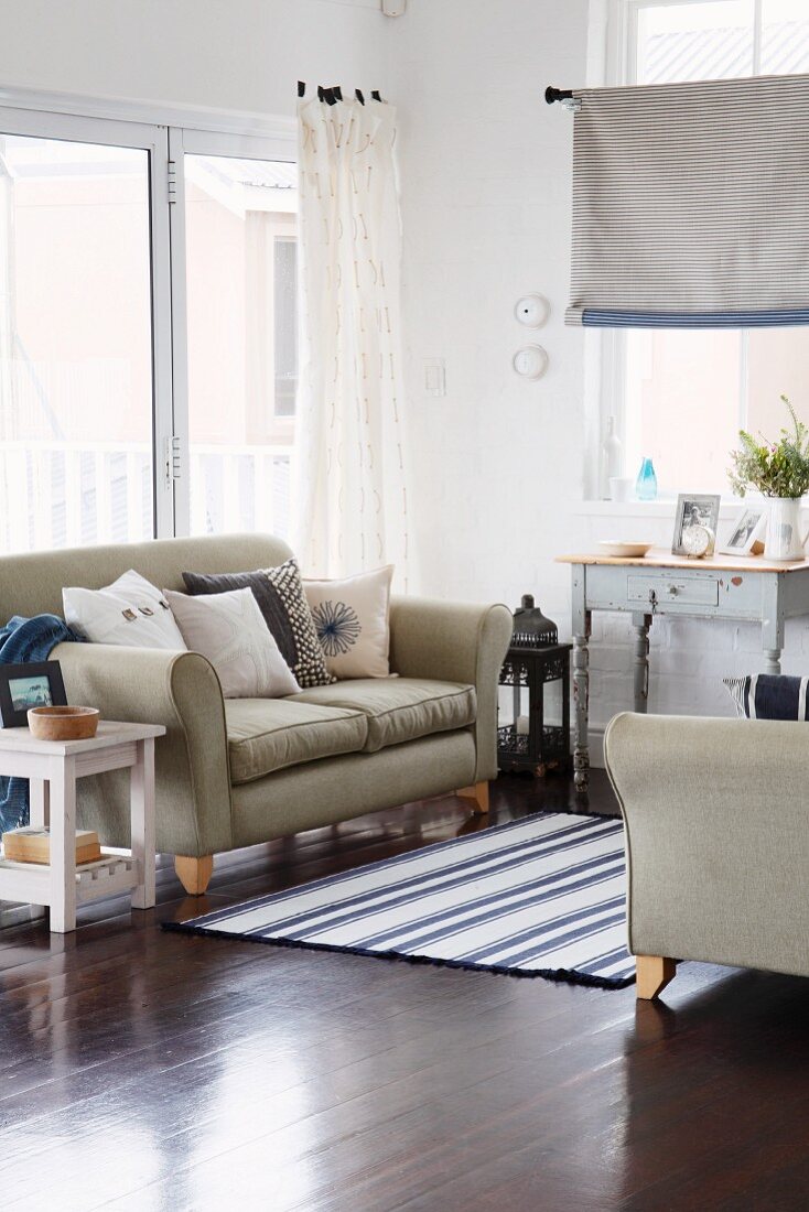 Blauweisse Kissen und ein Webteppich als Dekoration für eine lichtdurchflutete Sitzecke mit zwei Sofas