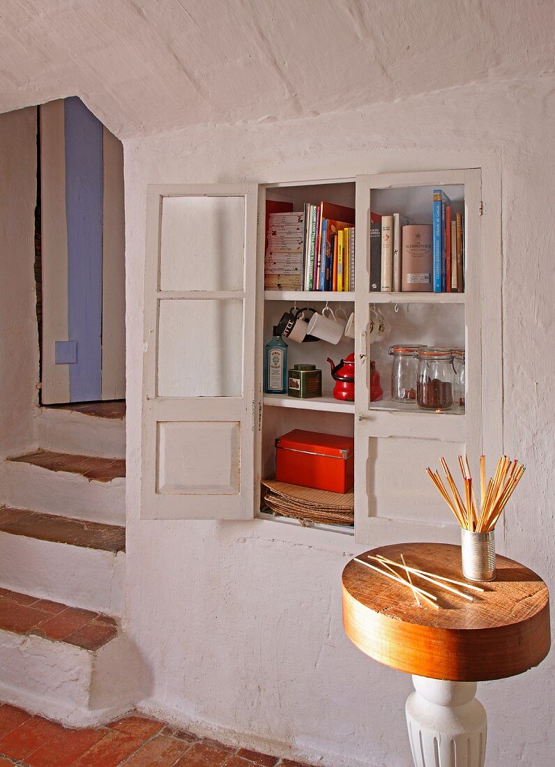 Becher mit Knabberstangen auf Beistelltisch vor Wandnische mit eingebautem Schrank in mediterranem Zimmer