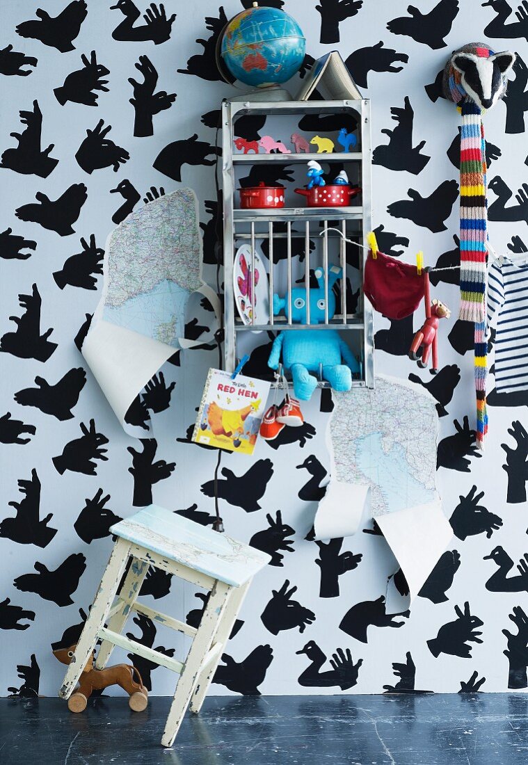Stool & toys on shelves against wallpaper with pattern of hand shadow animals