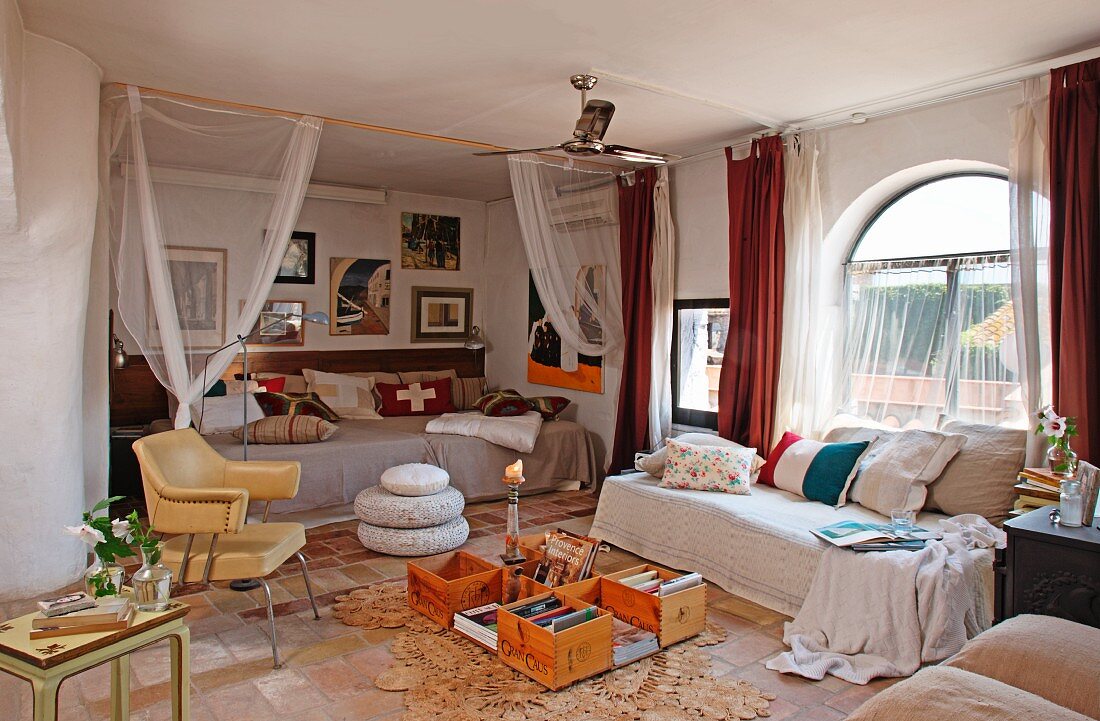 Gemütliches Tagesbett mit Kissen am Rundbogenfenster und improvisierter Bodentisch vor Rückzugsbereich in Nische