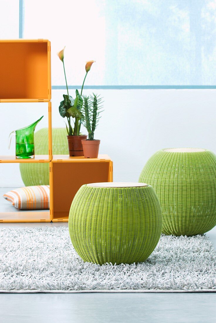 Bauchige grüne Hocker auf Teppich aus Spaltleder und Würfelregal aus Kunststoff
