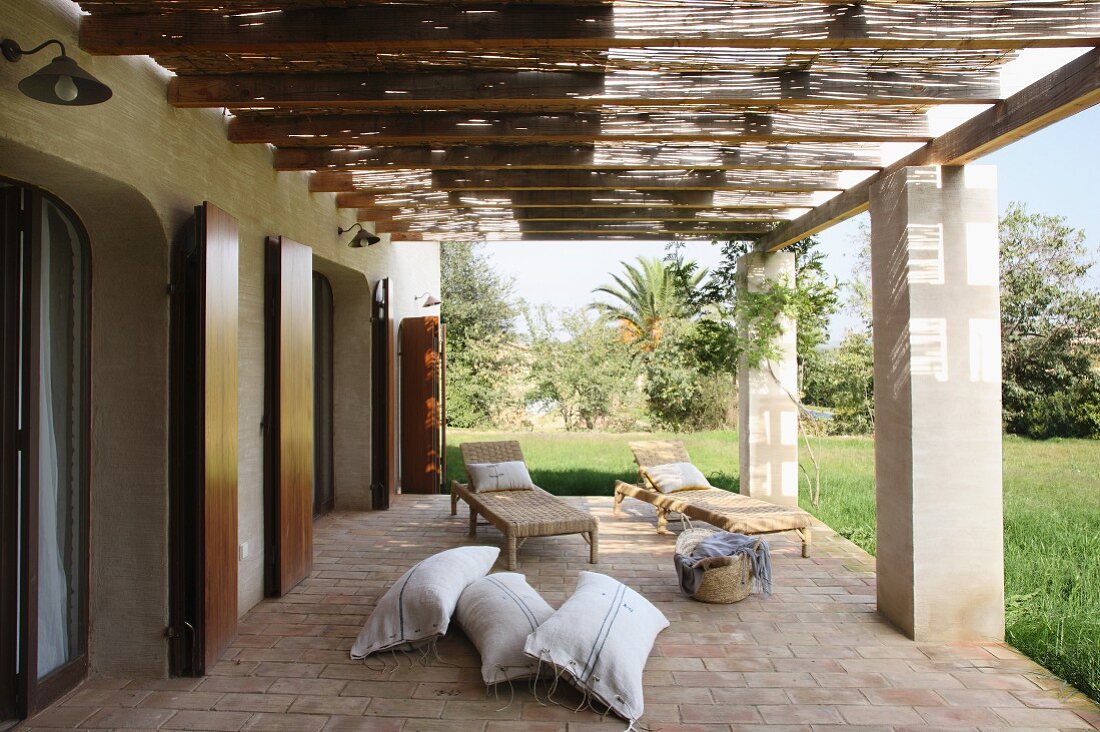 Terrasse mit Pergola auf Betonstützen vor mediterranem Haus und Blick in Garten